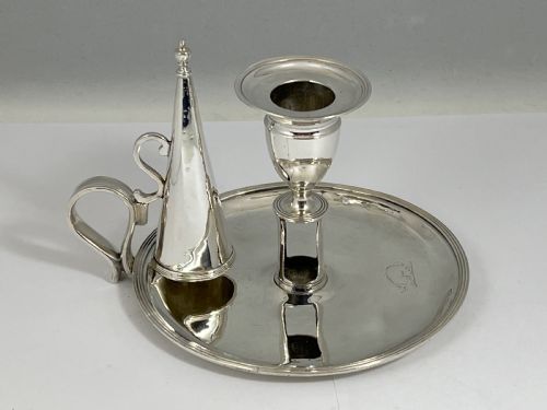 fig 1. A George III sterling silver chamberstick featuring a circular base pan, a raised central candle socket, a curved side handle, and a removable conical snuffer.