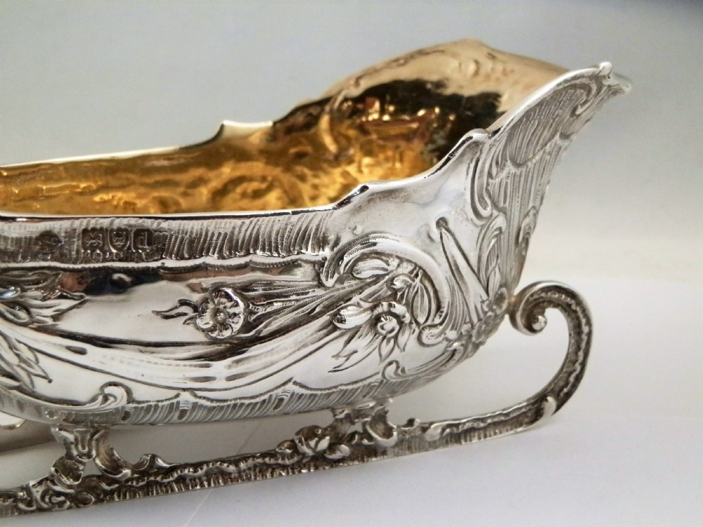 A pair of late Victorian sterling silver sleigh-shaped sauce boats with ornate rococo repousse detailing and gilded interiors. View X