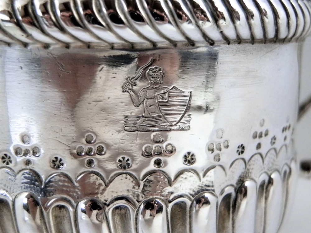 A 1694 William and Mary sterling silver porringer with twin scroll handles, rope-moulded girdle, lower spiral fluting, and an engraved armorial crest. View III