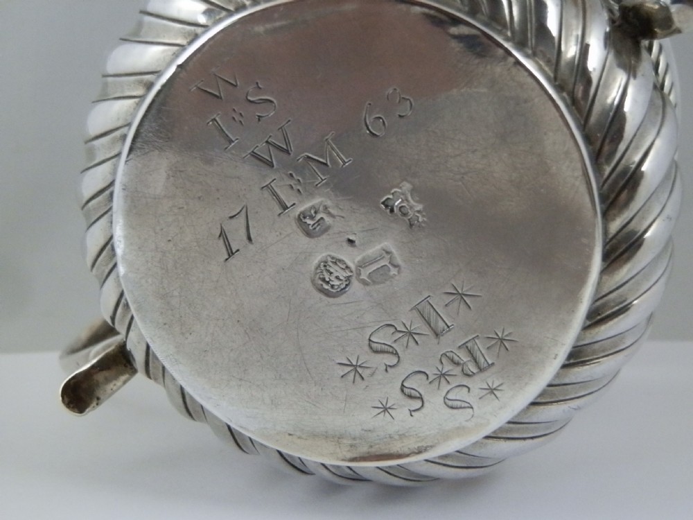 A 1694 William and Mary sterling silver porringer with twin scroll handles, rope-moulded girdle, lower spiral fluting, and an engraved armorial crest. View VII