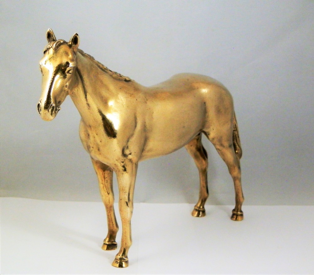 A side-profile view of a gold-coloured silver gilt sculpture depicting a standing racehorse with a detailed mane and muscular structure. View IV