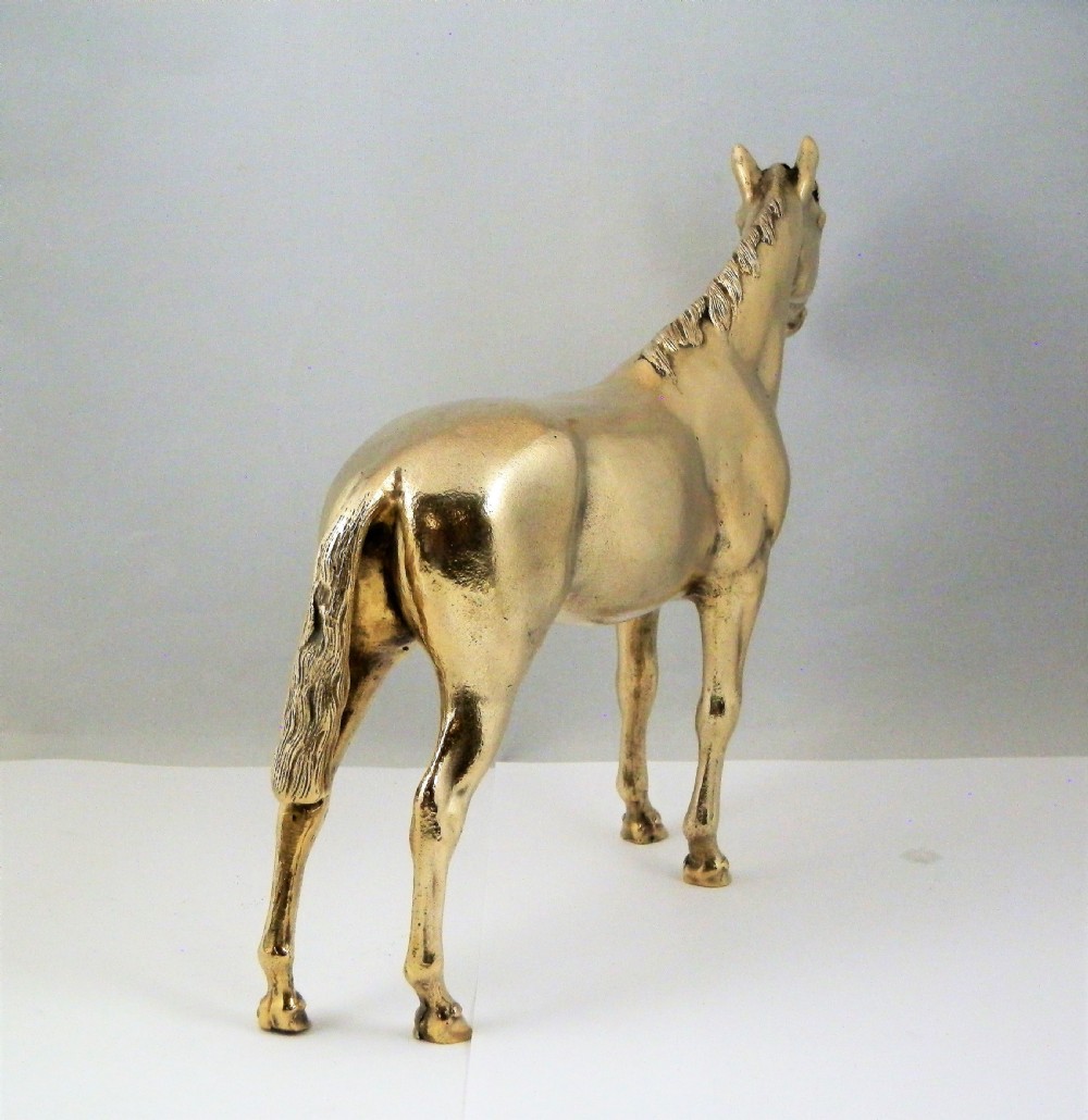 A side-profile view of a gold-coloured silver gilt sculpture depicting a standing racehorse with a detailed mane and muscular structure. View VII