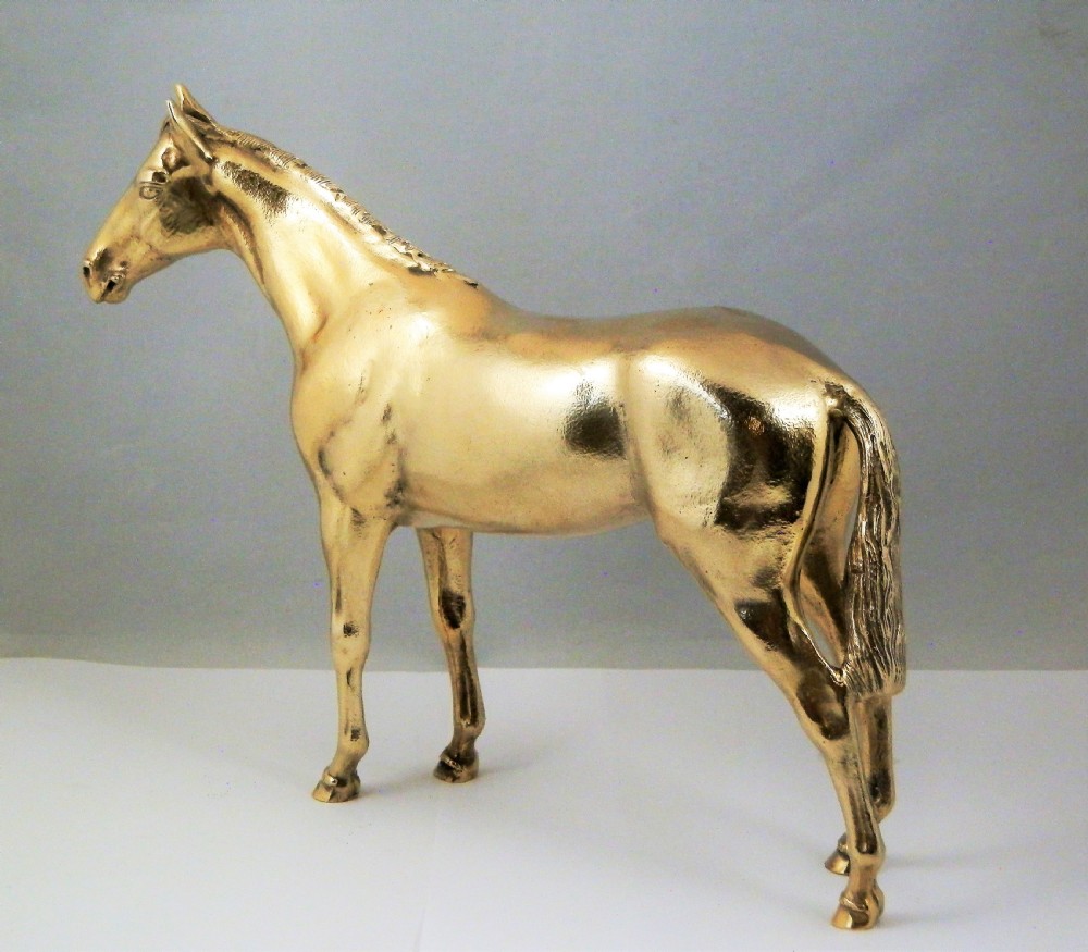A side-profile view of a gold-coloured silver gilt sculpture depicting a standing racehorse with a detailed mane and muscular structure. View VIII