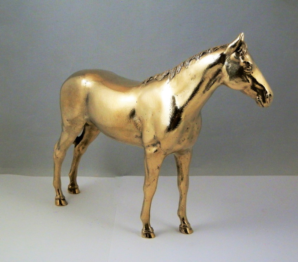 A side-profile view of a gold-coloured silver gilt sculpture depicting a standing racehorse with a detailed mane and muscular structure. View IX