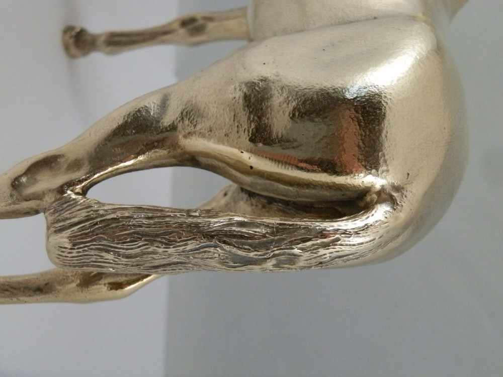 A side-profile view of a gold-coloured silver gilt sculpture depicting a standing racehorse with a detailed mane and muscular structure. View XI