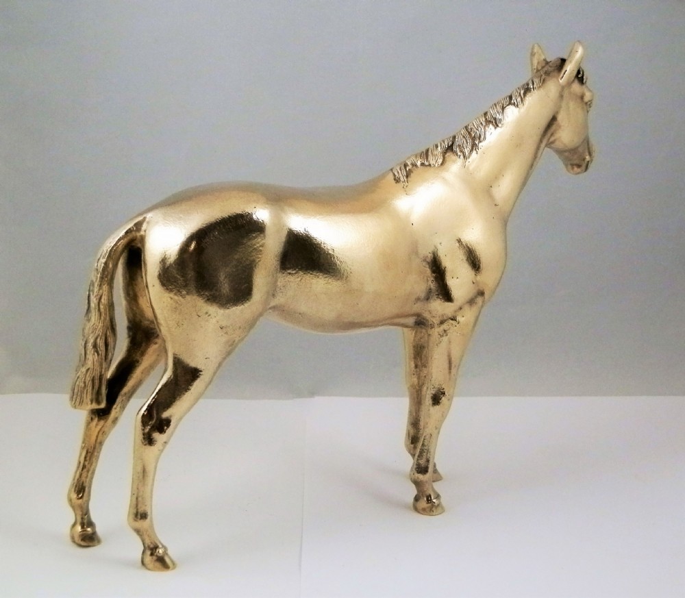 A side-profile view of a gold-coloured silver gilt sculpture depicting a standing racehorse with a detailed mane and muscular structure. View XIV