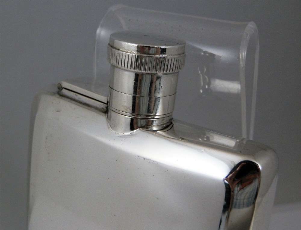 A polished rectangular silver Art Deco hip flask featuring a knurled bayonet cap and curved pocket profile. View II
