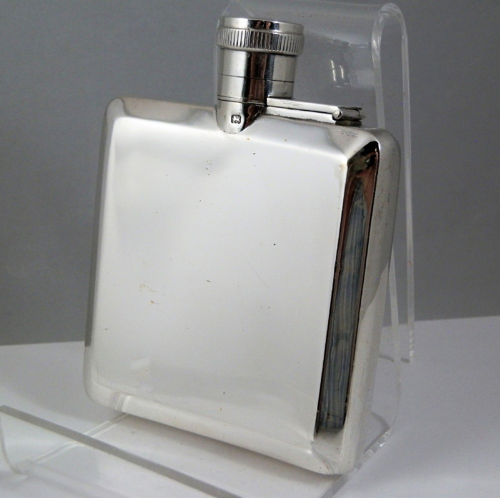 A polished rectangular silver Art Deco hip flask featuring a knurled bayonet cap and curved pocket profile. View III