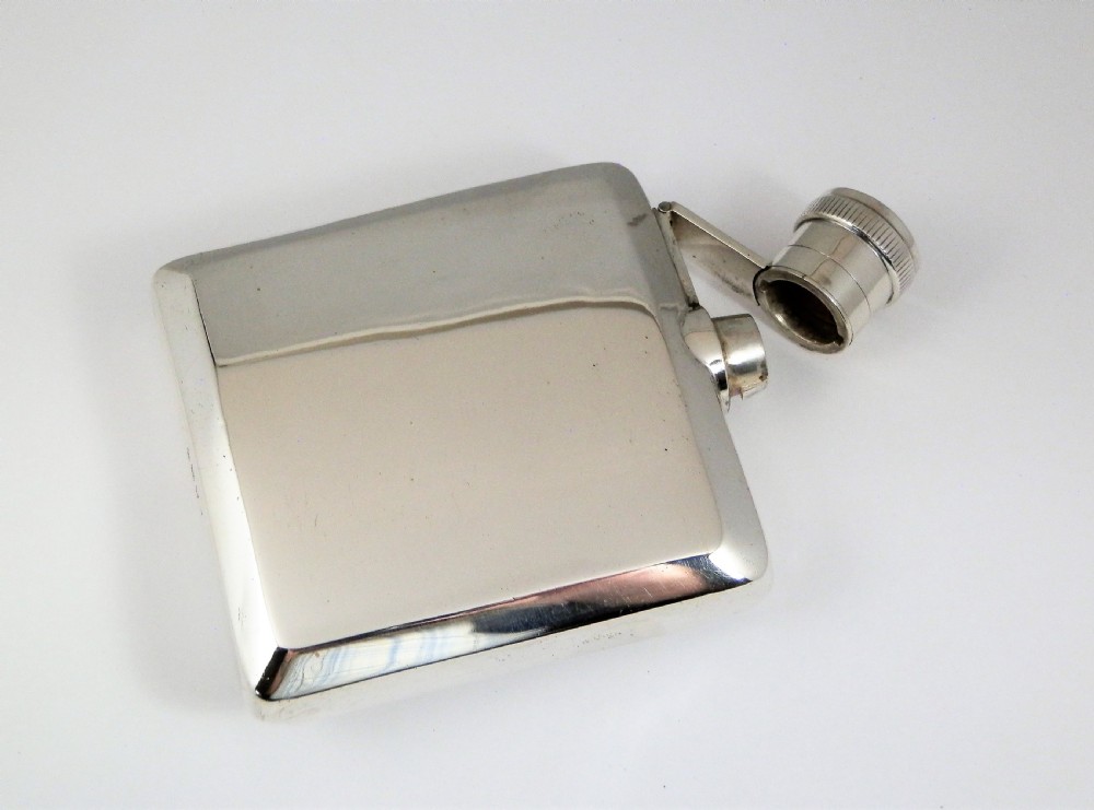 A polished rectangular silver Art Deco hip flask featuring a knurled bayonet cap and curved pocket profile. View VIII