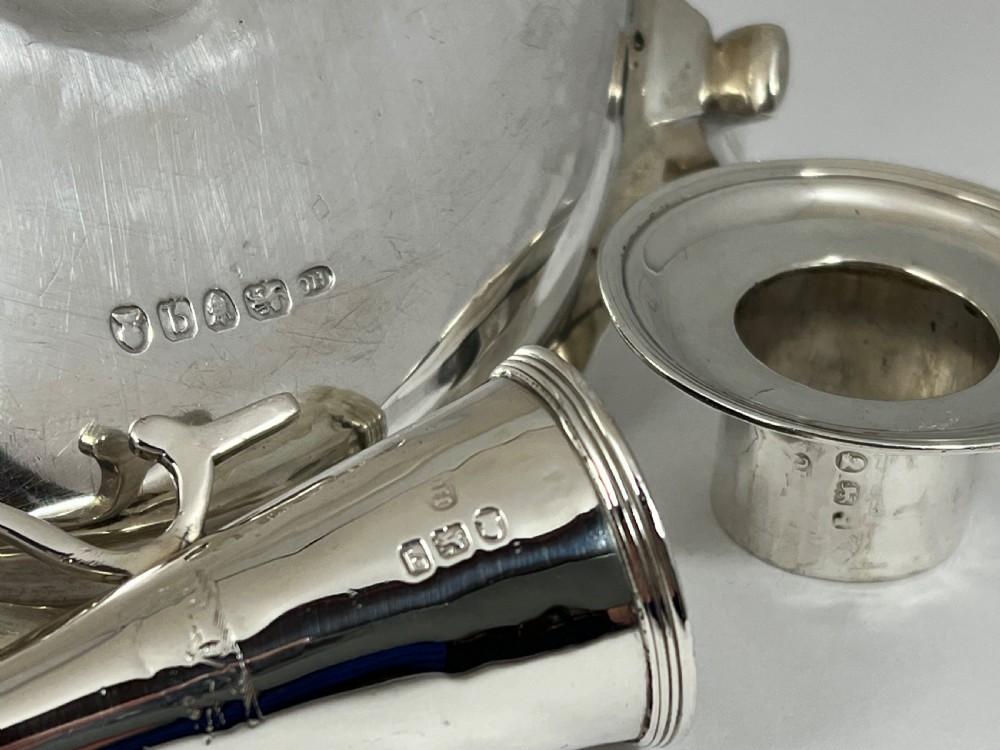 A George III sterling silver chamberstick featuring a circular base pan, a raised central candle socket, a curved side handle, and a removable conical snuffer. View V