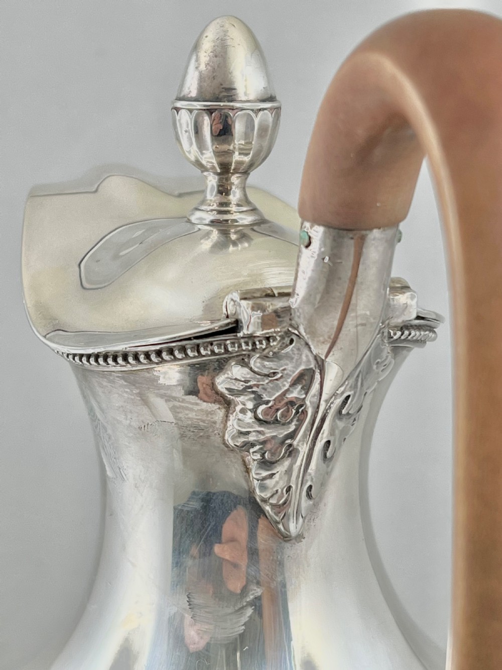 An urn-shaped sterling silver ewer with beaded border trim, a pinecone finial, and a high arched wooden handle. View III