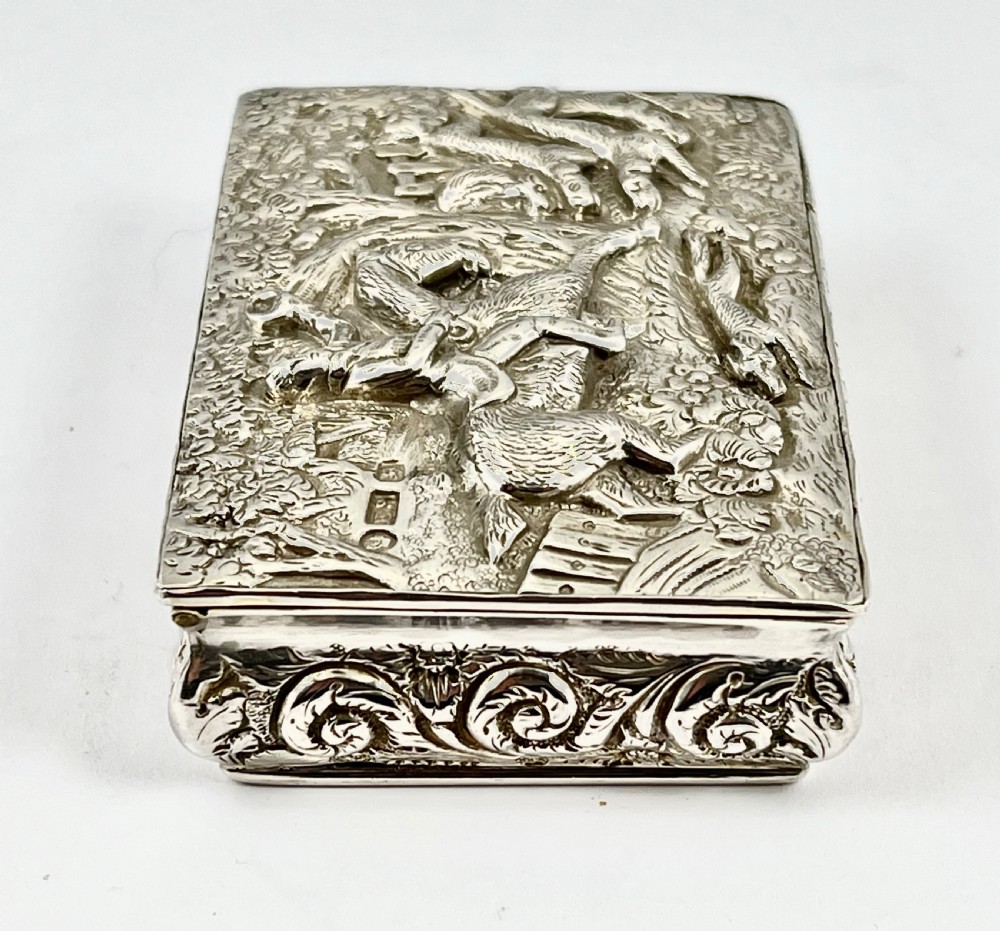 Rectangular sterling silver snuff box featuring a relief-carved hunting scene with a rider on horseback surrounded by hounds in a woodland setting. View IV