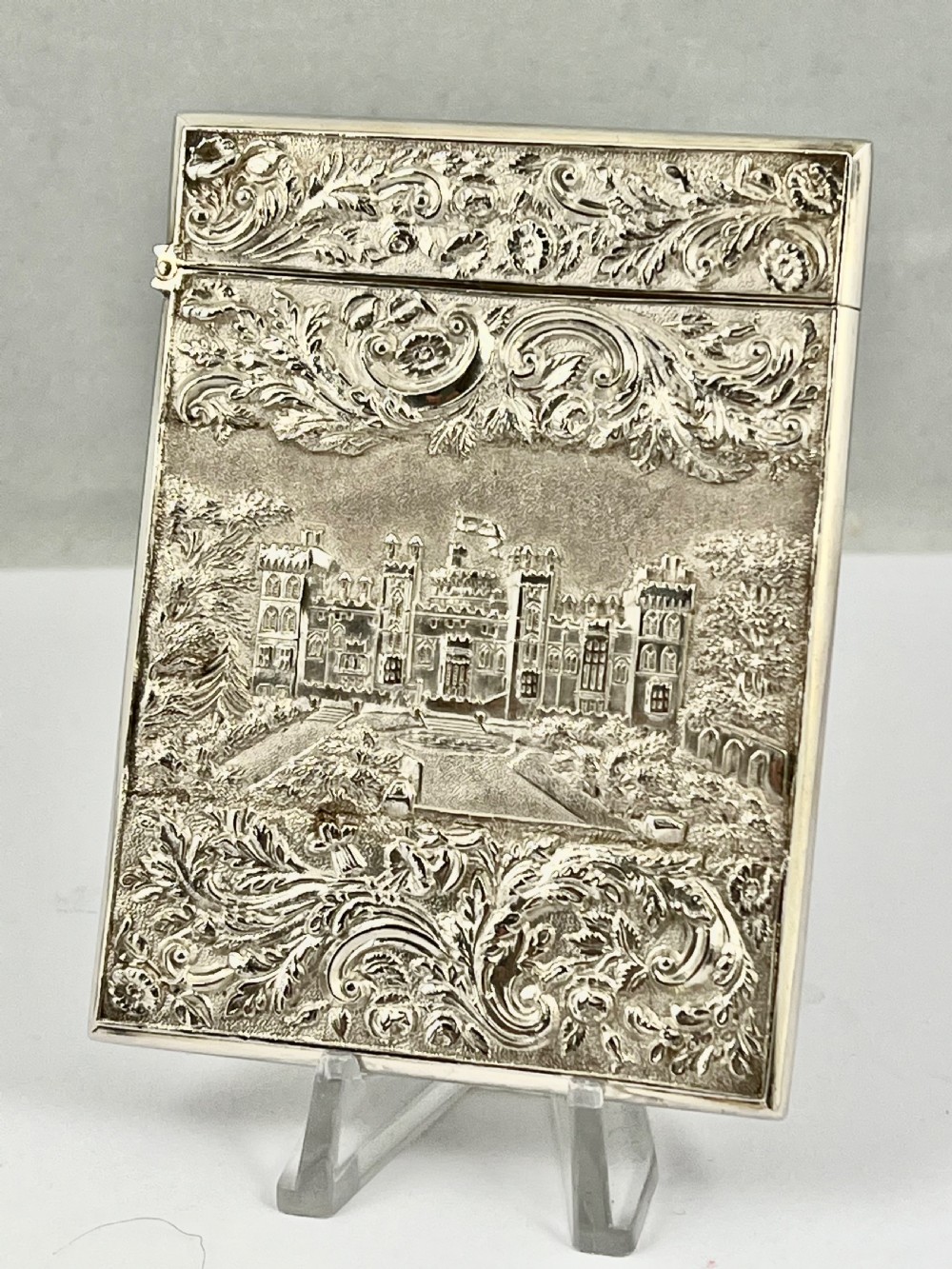 An Early Victorian sterling silver card case featuring detailed high-relief repousse carving of an architectural estate framed by scrollwork. View II