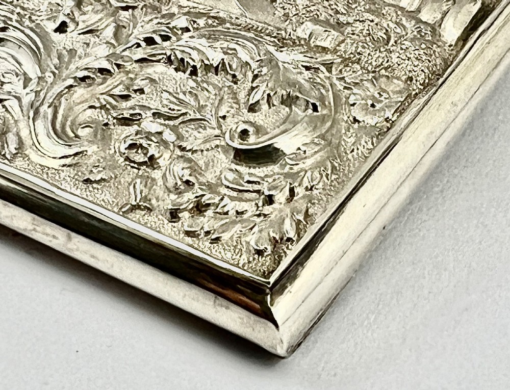 An Early Victorian sterling silver card case featuring detailed high-relief repousse carving of an architectural estate framed by scrollwork. View IV