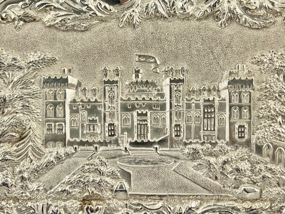 An Early Victorian sterling silver card case featuring detailed high-relief repousse carving of an architectural estate framed by scrollwork. View V