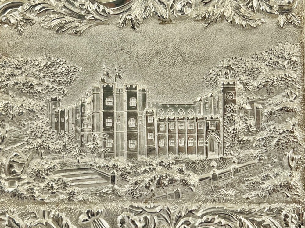 An Early Victorian sterling silver card case featuring detailed high-relief repousse carving of an architectural estate framed by scrollwork. View VI