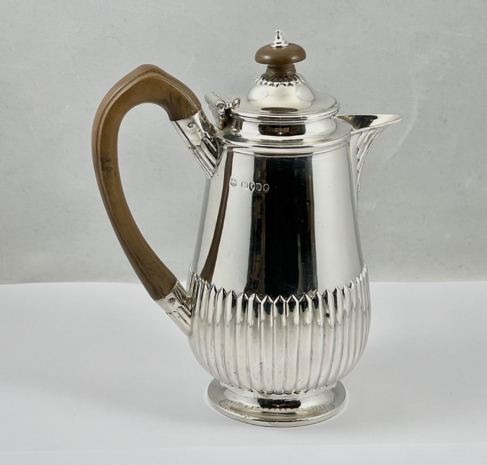 Victorian sterling silver hot water pot featuring a fluted lower body, hinged lid, and carved wooden handle. View II