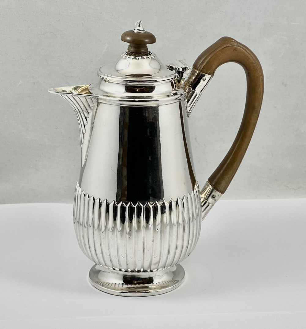 Victorian sterling silver hot water pot featuring a fluted lower body, hinged lid, and carved wooden handle. View III