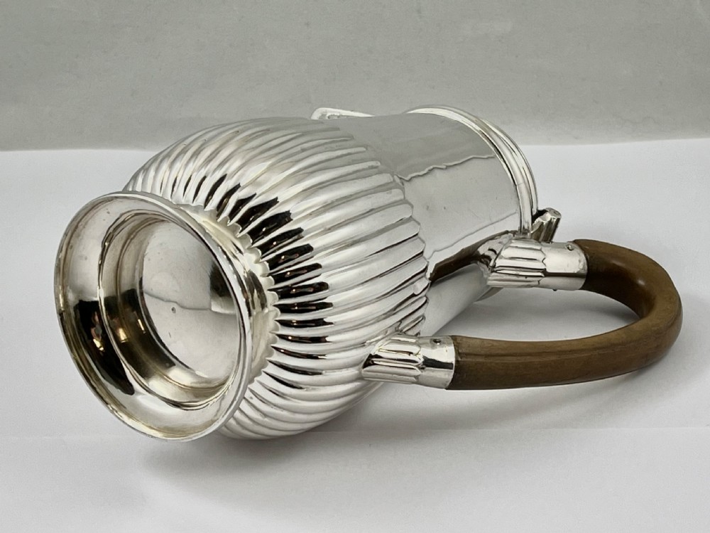 Victorian sterling silver hot water pot featuring a fluted lower body, hinged lid, and carved wooden handle. View IX