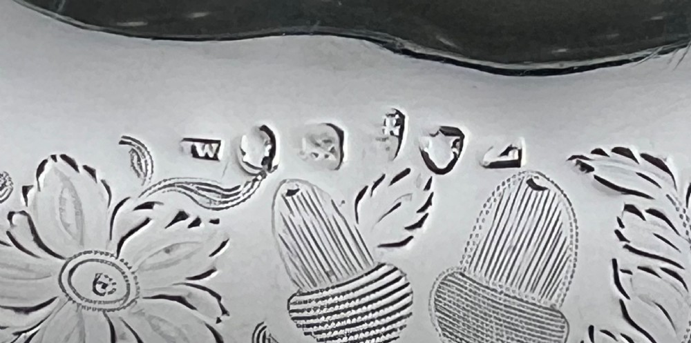 A round sterling silver bread basket featuring an overhead swing handle, floral engraving, a shell-detailed rim, and a fluted pedestal base. View IV
