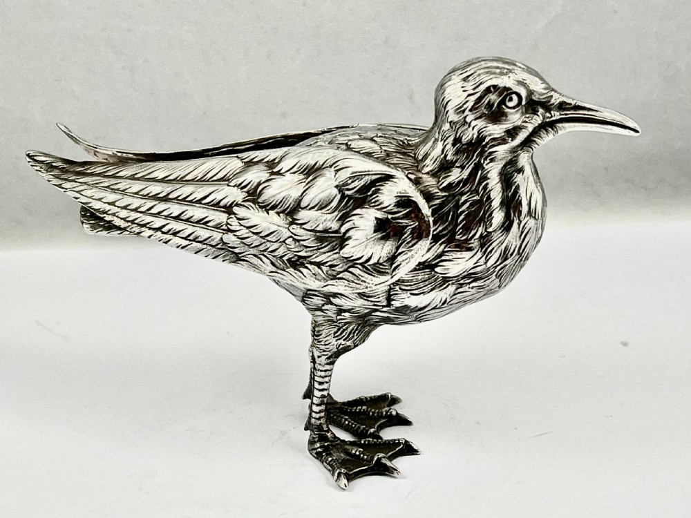A chased Edwardian silver model of a wading bird with textured feather detail and webbed feet, shown in profile facing left. View III