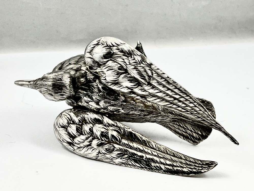 A chased Edwardian silver model of a wading bird with textured feather detail and webbed feet, shown in profile facing left. View V