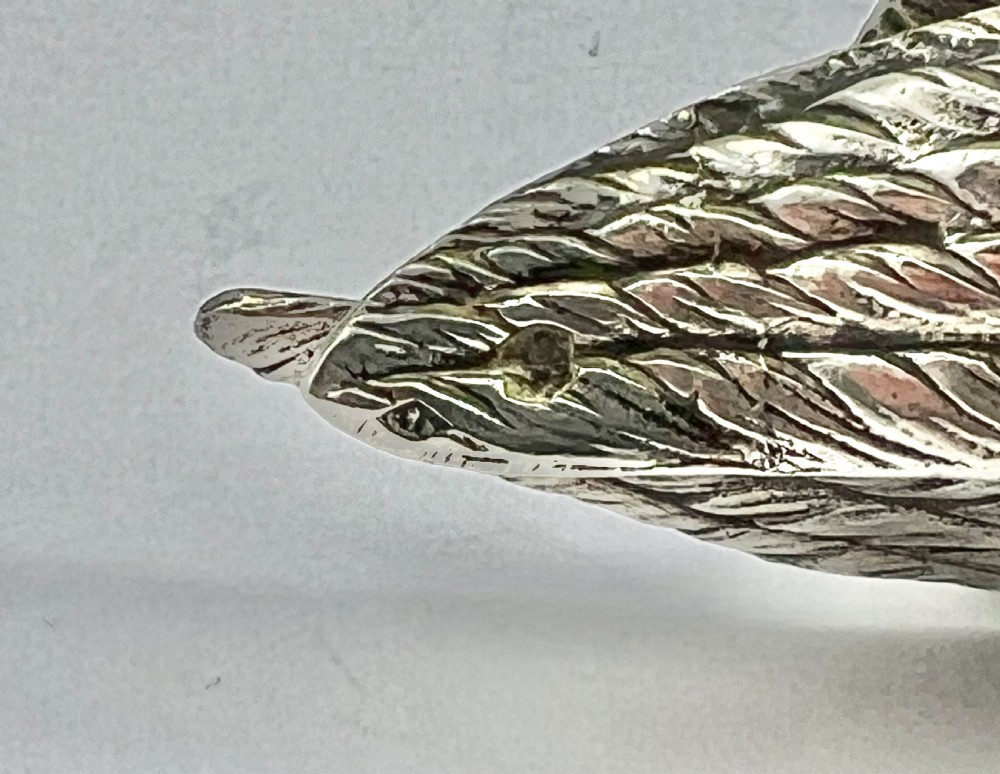 A chased Edwardian silver model of a wading bird with textured feather detail and webbed feet, shown in profile facing left. View IX