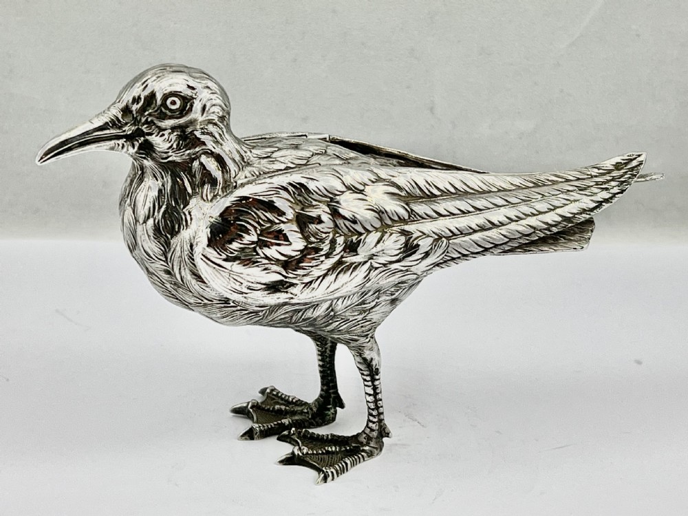 A chased Edwardian silver model of a wading bird with textured feather detail and webbed feet, shown in profile facing left. View XI