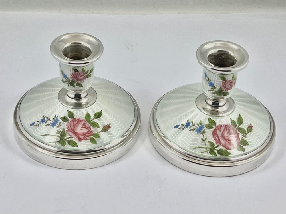A pair of Elizabeth II sterling silver candlesticks featuring engine-turned white enamel bases and stems adorned with painted pink roses. View II