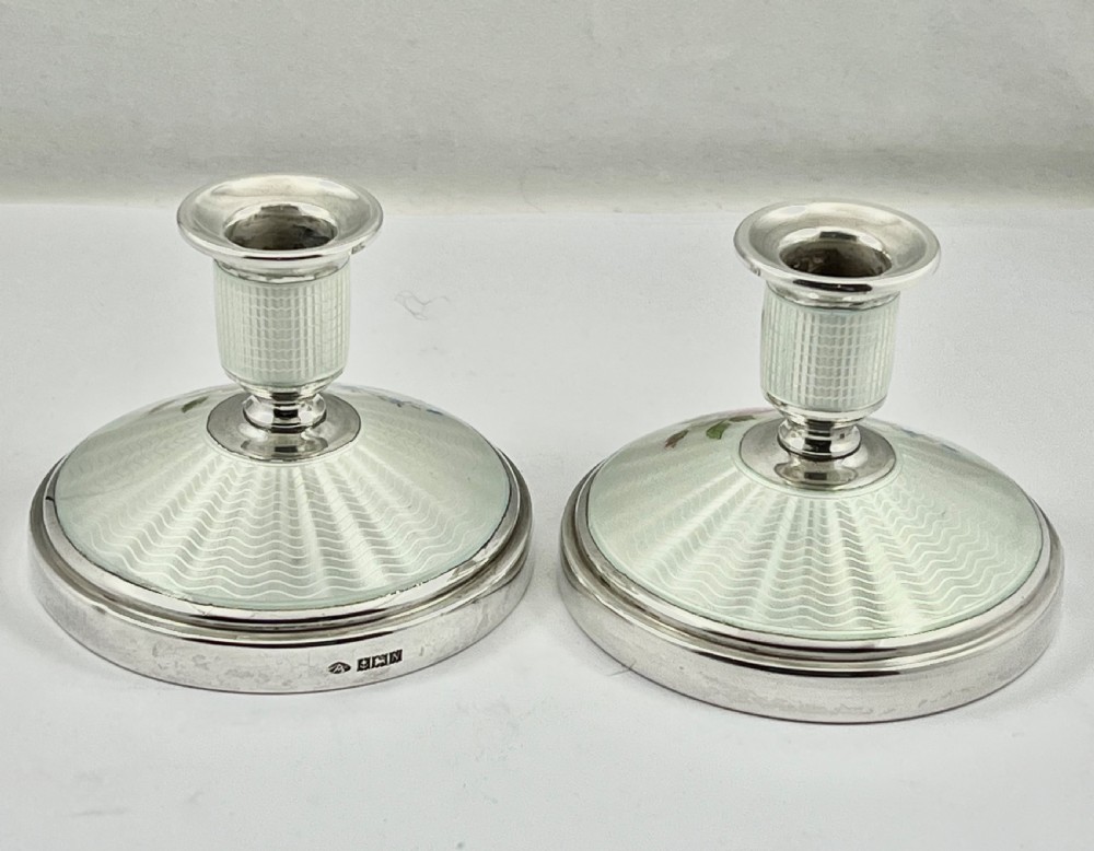 A pair of Elizabeth II sterling silver candlesticks featuring engine-turned white enamel bases and stems adorned with painted pink roses. View VIII