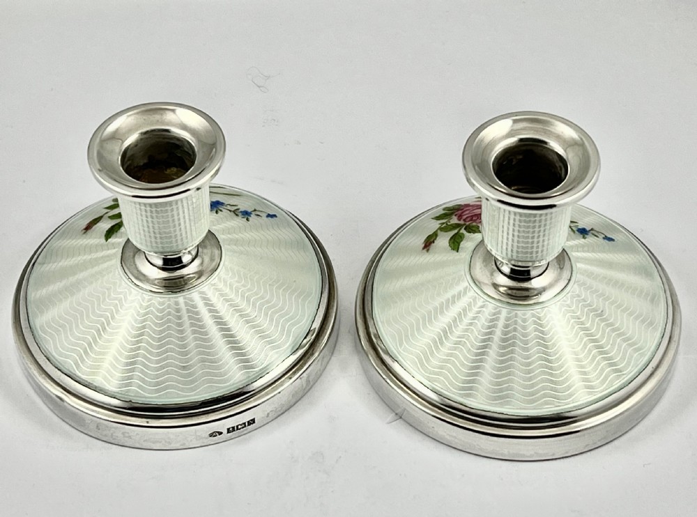 A pair of Elizabeth II sterling silver candlesticks featuring engine-turned white enamel bases and stems adorned with painted pink roses. View IX