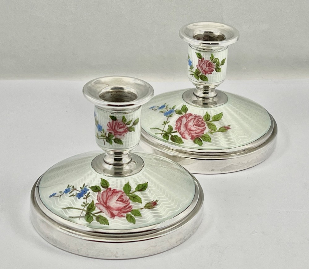 A pair of Elizabeth II sterling silver candlesticks featuring engine-turned white enamel bases and stems adorned with painted pink roses. View X