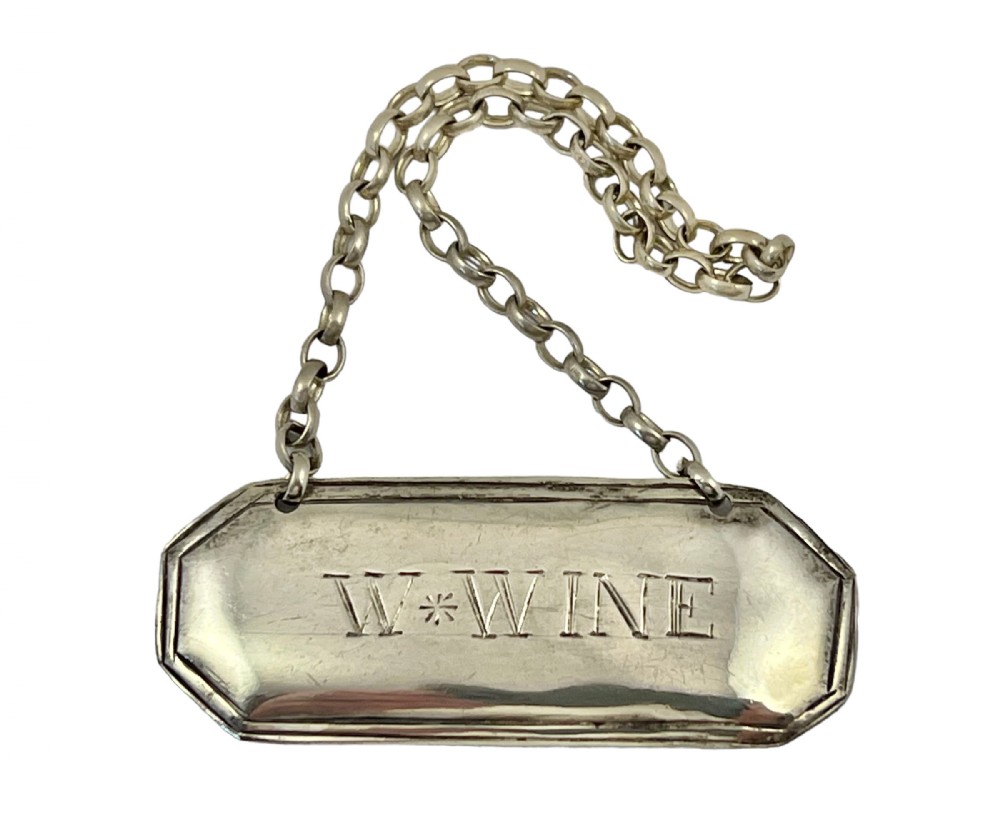 A Georgian Scottish provincial silver rectangular decanter label with canted corners engraved W WINE suspended from a silver link chain.