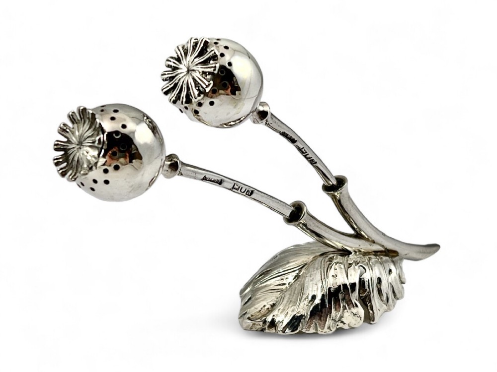 A late Victorian sterling silver double pomander modeled as two poppy seed heads resting on a leafy base with visible hallmarks.