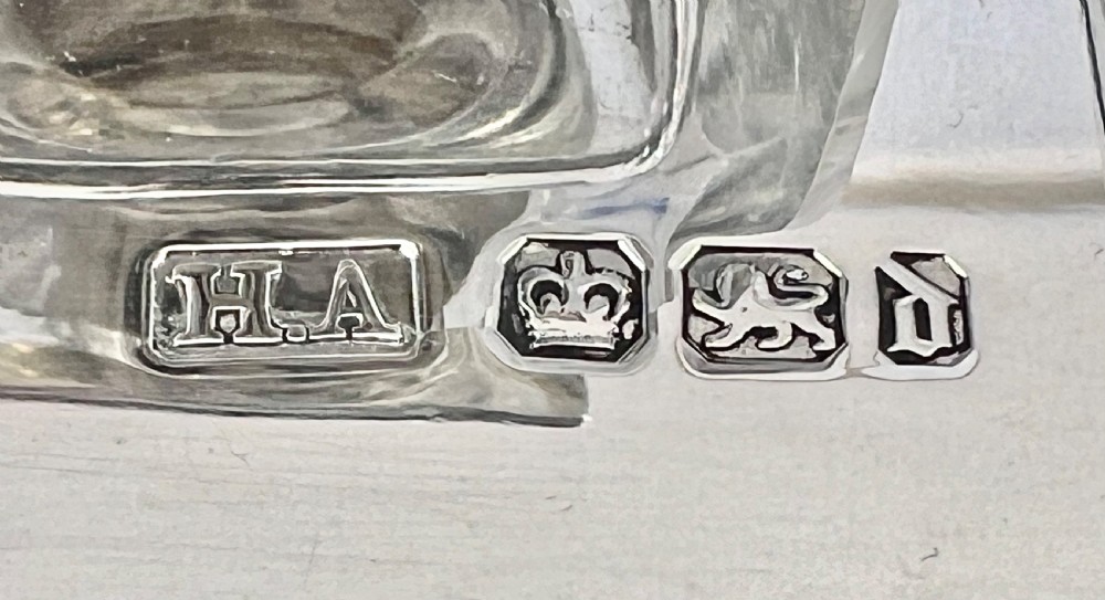 A late Victorian sterling silver inkstand set featuring two cut glass inkwells with silver caps, a central covered box, and a pen tray enclosed by a gallery rail. View X