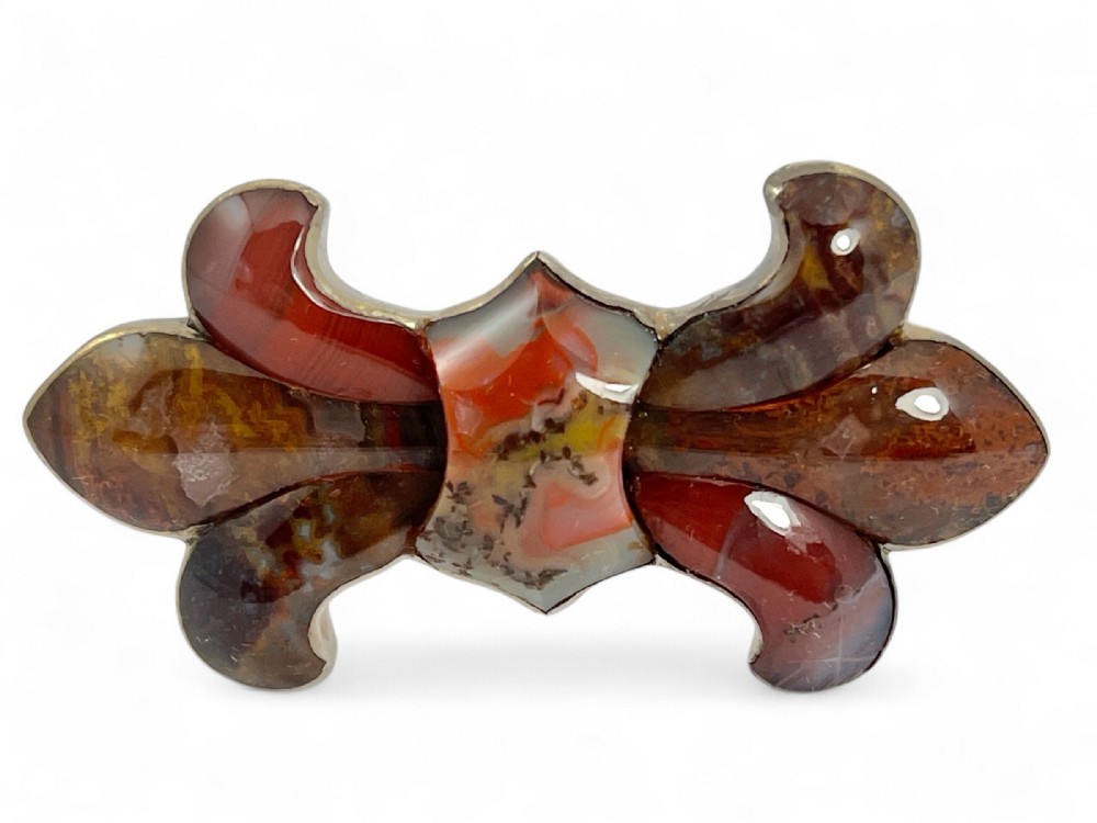 A Victorian silver brooch featuring inlaid multi-coloured agate stones arranged in a stylised bow shape.