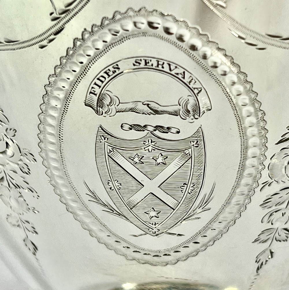 A George III two-handled sterling silver cup with bright-cut engraving, an armorial crest, and a stepped circular pedestal base. View VIII