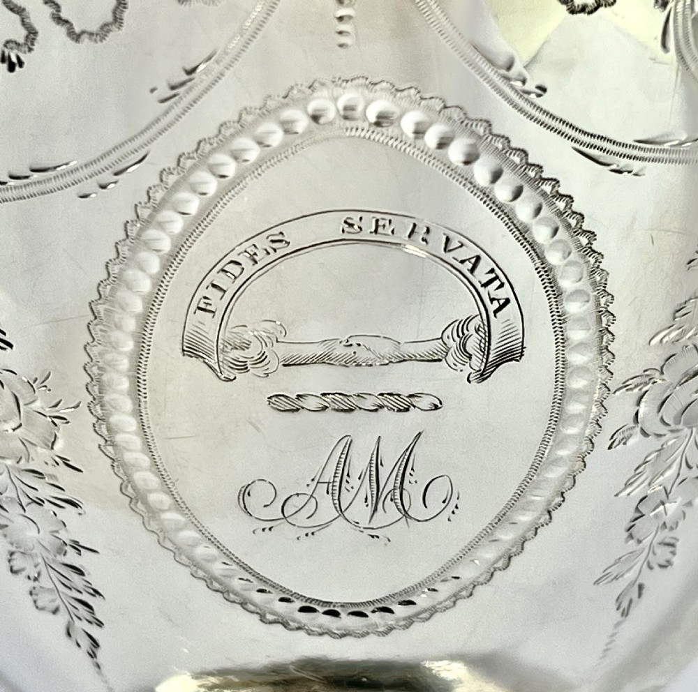 A George III two-handled sterling silver cup with bright-cut engraving, an armorial crest, and a stepped circular pedestal base. View IX