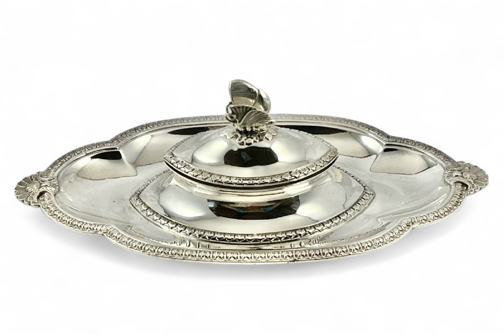 A Victorian sterling silver shaped inkstand tray featuring a central lid topped with a butterfly finial and decorative scalloped borders.