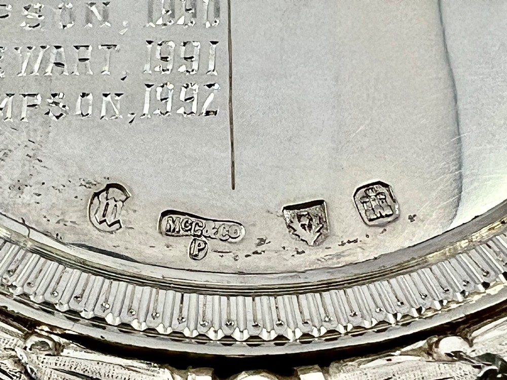 An Edwardian silver oval curling medal featuring crossed brooms at the top, a central engraved portrait of a man, and an inscribed silver border. View XIII