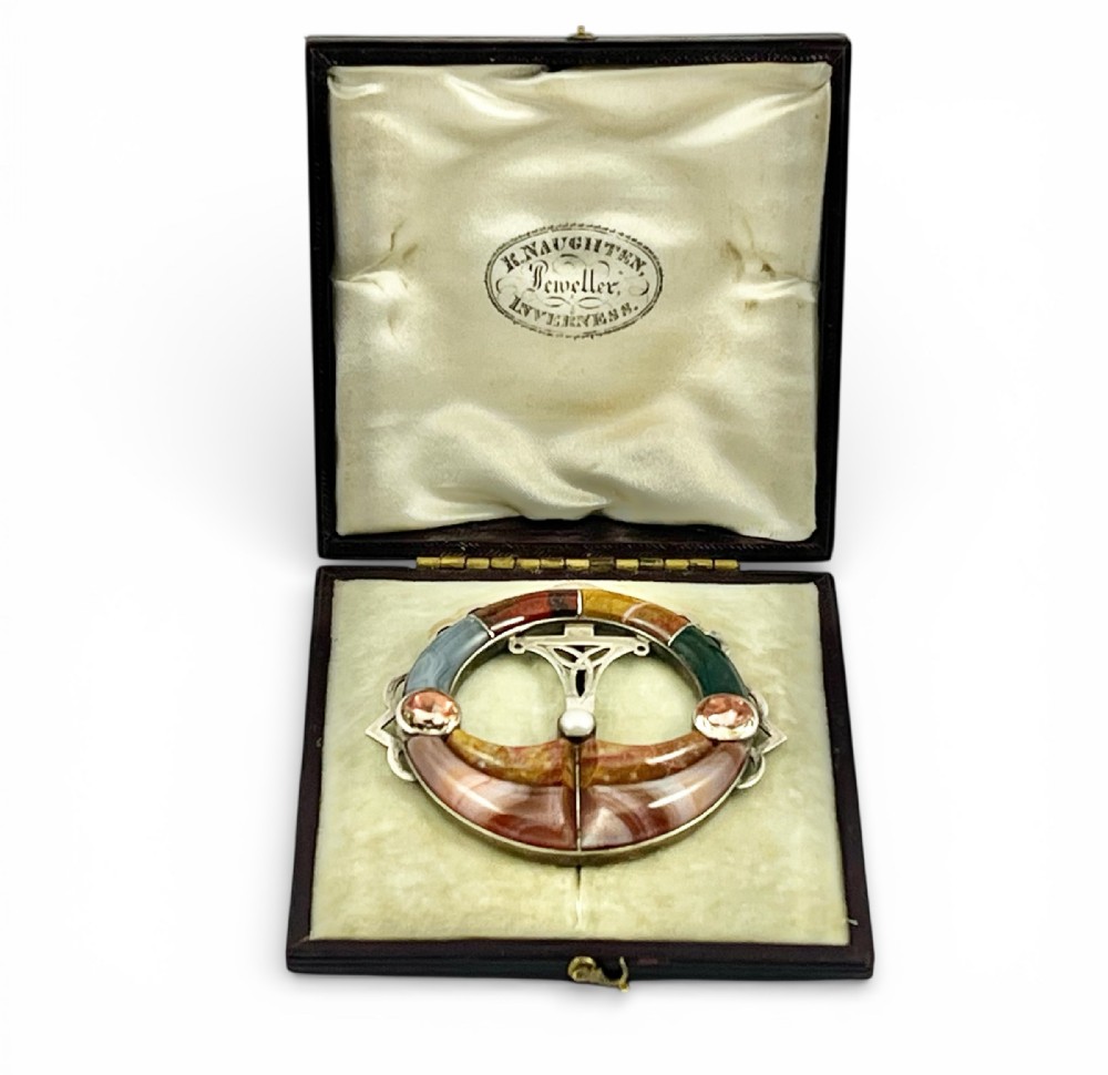 An early Victorian circular silver brooch inlaid with segmented polished Scottish agates and jaspers surrounding a central Celtic motif.