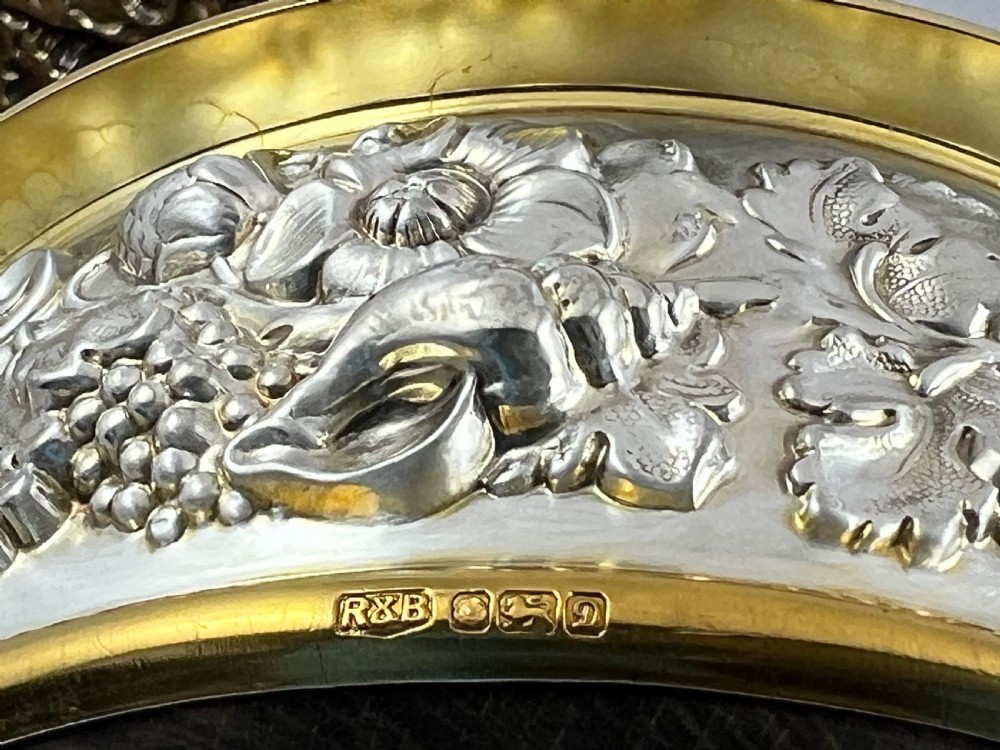 A pair of circular sterling silver and gilt wine coasters with floral repousse borders and concentric-turned wooden base inserts. View XII