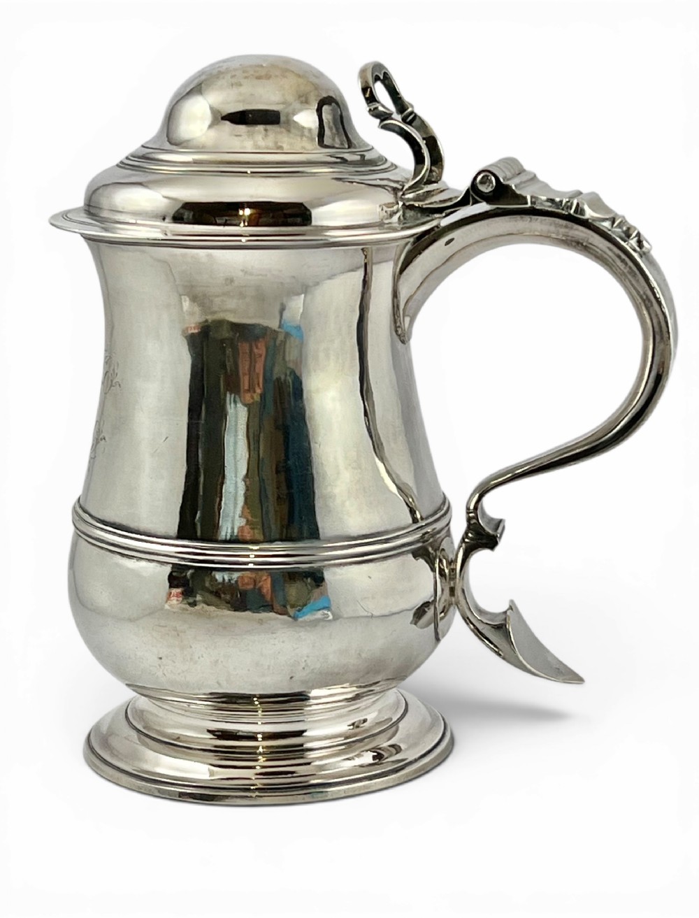 A sterling silver George III lidded tankard featuring a domed hinged cover, double-scroll handle with thumbpiece, and a moulded central body ring on a stepped pedestal base.