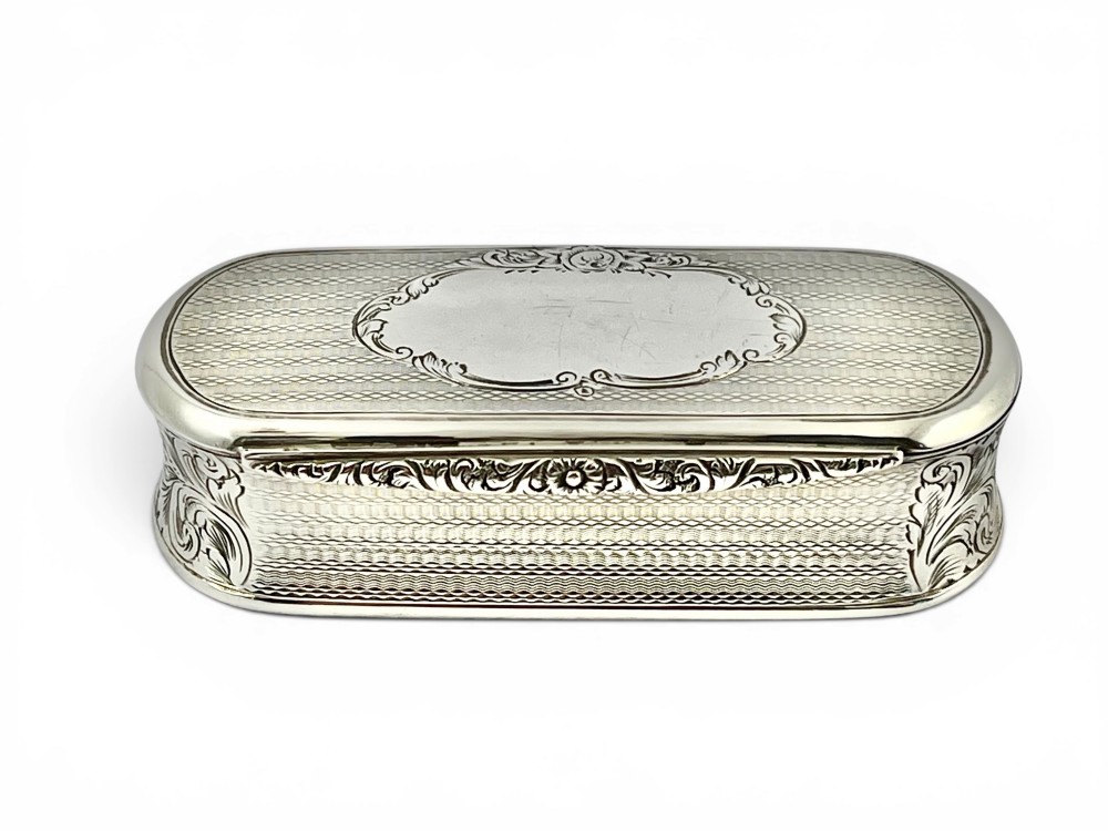 An antique Victorian sterling silver oblong table snuff box featuring engine-turned geometric engraving and an unengraved oval central cartouche on the hinged lid.