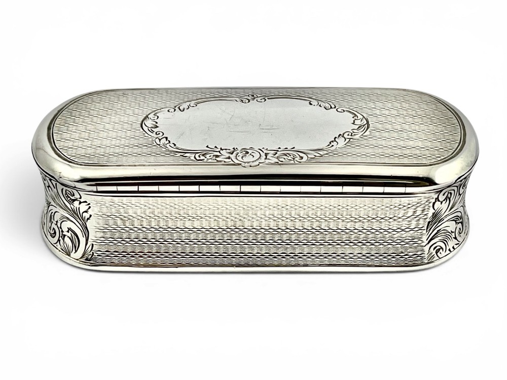 An antique Victorian sterling silver oblong table snuff box featuring engine-turned geometric engraving and an unengraved oval central cartouche on the hinged lid. View II