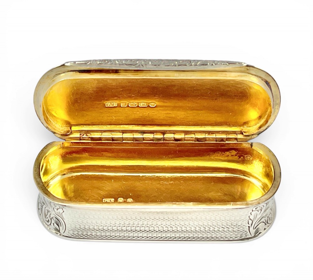 An antique Victorian sterling silver oblong table snuff box featuring engine-turned geometric engraving and an unengraved oval central cartouche on the hinged lid. View IV