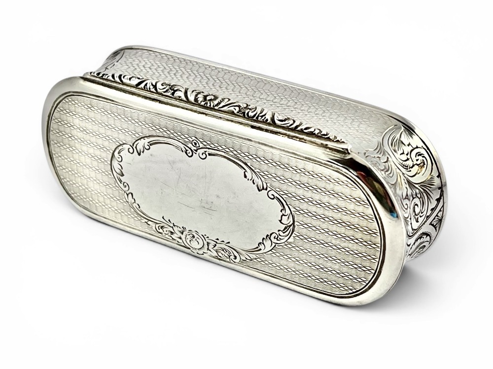 An antique Victorian sterling silver oblong table snuff box featuring engine-turned geometric engraving and an unengraved oval central cartouche on the hinged lid. View V