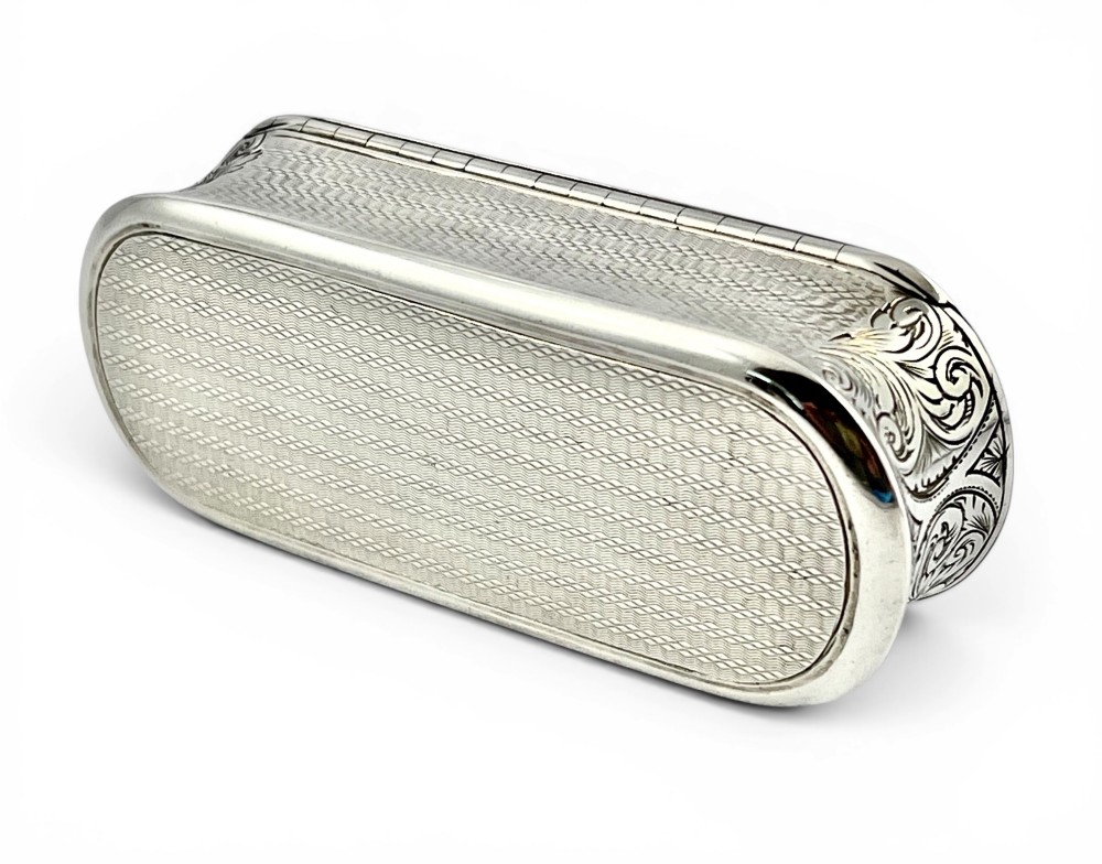 An antique Victorian sterling silver oblong table snuff box featuring engine-turned geometric engraving and an unengraved oval central cartouche on the hinged lid. View VI