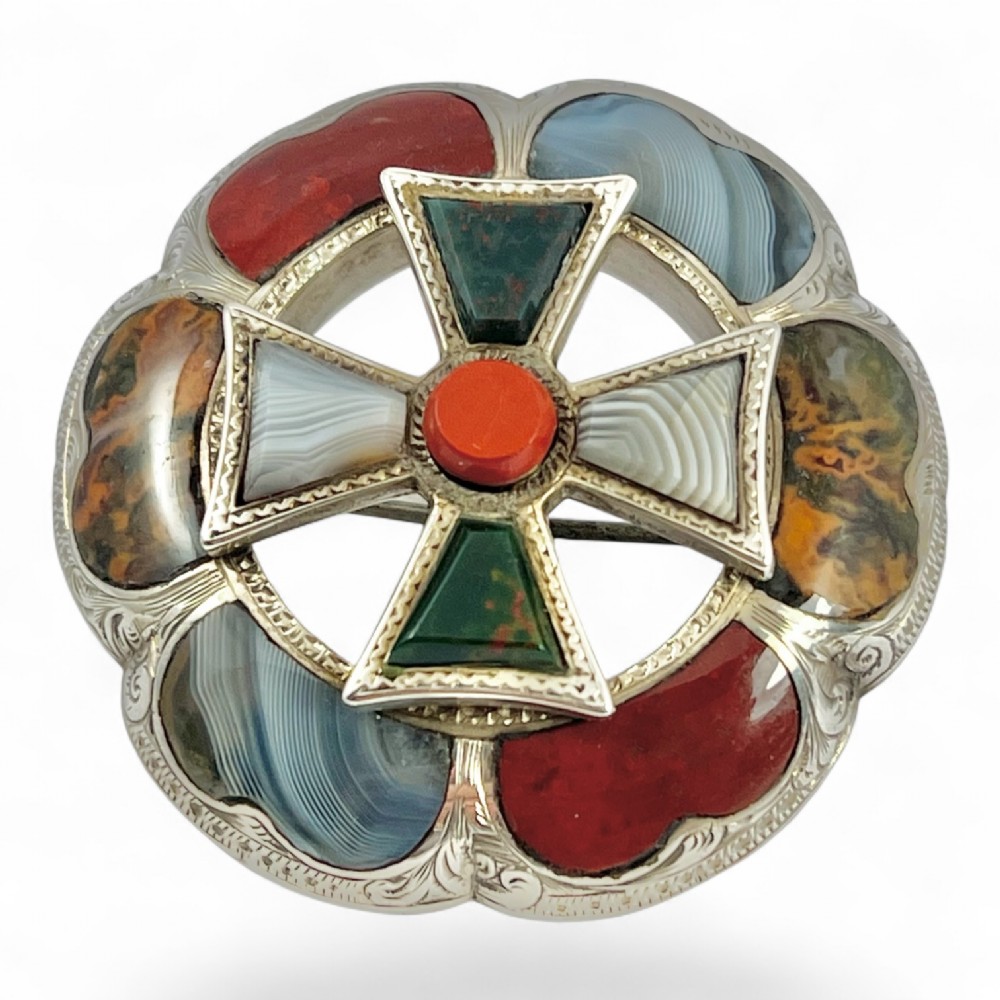 A circular Victorian Scottish silver brooch inlaid with polished agates, jasper, and bloodstone, featuring a central cross motif with engraved detailing. View IV