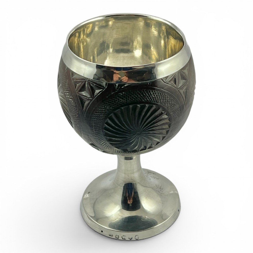 An eighteenth-century carved coconut shell goblet featuring intricate geometric starburst patterns, a silver rim, stem, and hallmarked circular base. View II